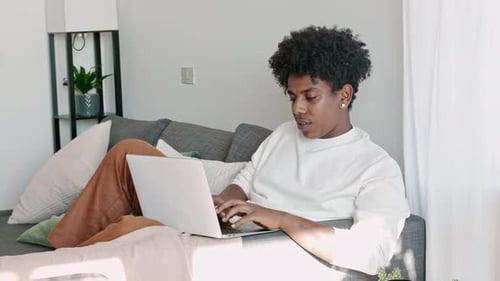 Young Adult Typing on Laptop at Home