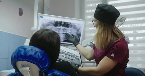 Dentist Reviews X-Ray With Patient in Modern Office