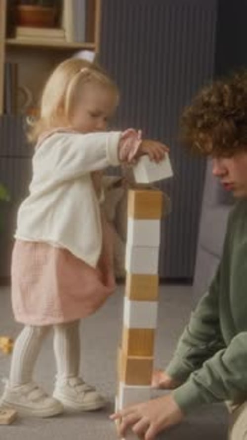 Little Girl Building Tall Tower with Brother Vertical