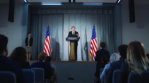 Man Speaks at Podium with American Flags