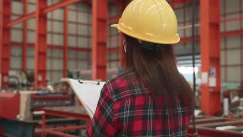 Back professional heavy Industry engineer woman worker wearing safety helmet using clipboard