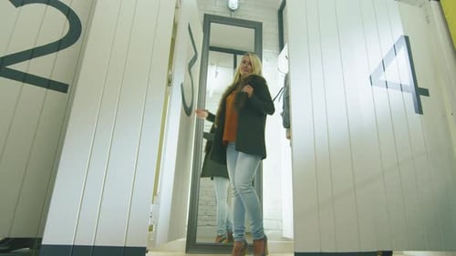 Jovem loira experimentando roupas de outono em um provador de uma loja de departamentos.