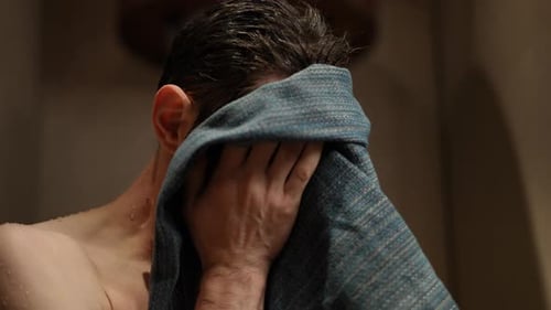 Man Drying Face with Blue Towel in Bathroom