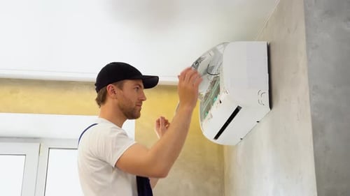 Technician Repairing Air Conditioner Filter in Home
