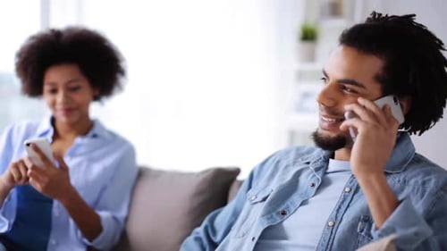 Attractive Couple Relaxing on Sofa with Mobile Phones