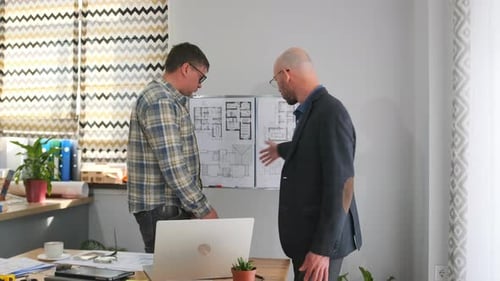 Architects Discussing Blueprints Together in Office