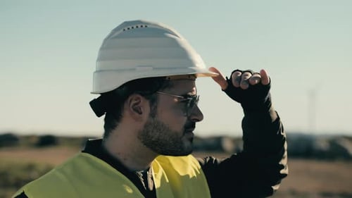 Renewable energy in action: an engineer surveys wind turbines on a sunny day, promoting clean energy