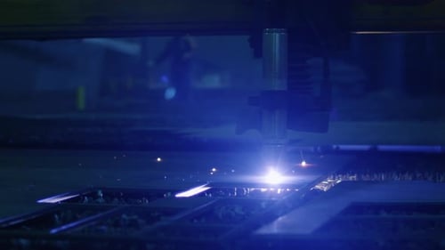Close-up footage of a CNC plasma cutter that is cutting out metal objects in a heavy industry facto