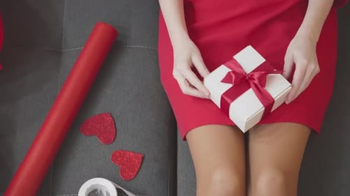 Woman Holds Gift Box With Ribbon on Couch
