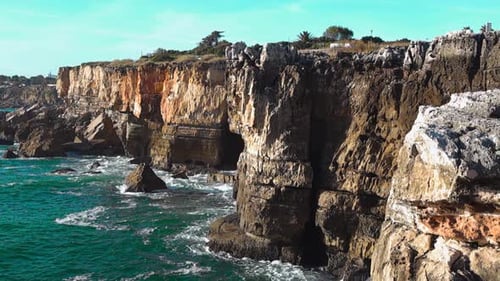 Dramatic High Cliffs And Sea Caves Along A Rugged Coastline
