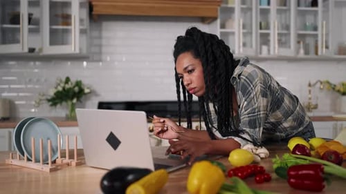 Woman Eating Lunch While Using Laptop in Kitchen