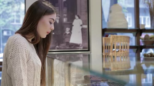 A Woman Admires the Delicious Pastries at the Bakery