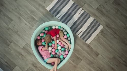 Un couple d'enfants heureux rampe dans une piscine sèche sous des balles en plastique