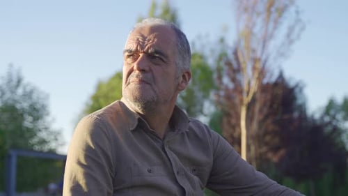 Senior Man Relaxing Outdoors in Sunny Park
