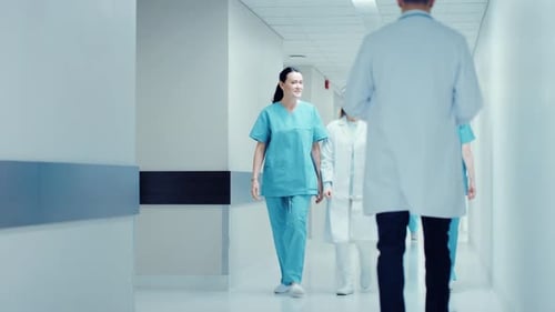 Female Surgeon and Female Doctor Walk Through Hospital Hallway Talking about Patient's Health. Mode