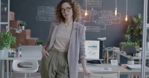 Slow Motion Portrait of Young Businesswoman in Suit Standing in Creative Office Smiling Looking at