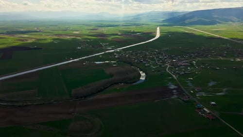 A large, lush green field with a dirt road running through it