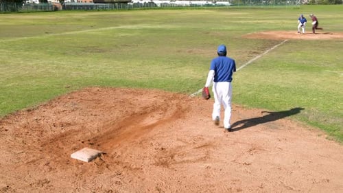 Playing baseball, pitcher throwing ball while batter running to first base