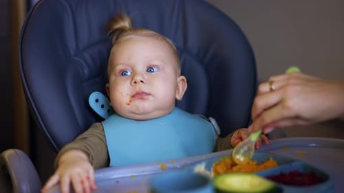 Happy Infant Being Fed in High Chair