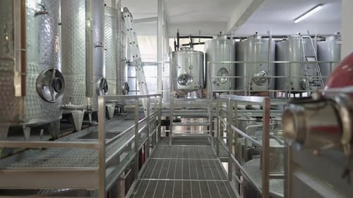 Innenaufnahmen der Alkoholproduktionsfabrik im Innenbereich. Reihen von Weinfässern aus Edelstahl