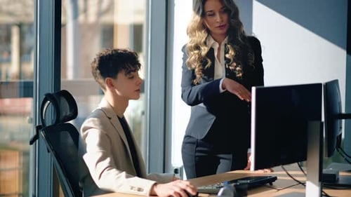 Man Working at Computer While Woman Looks On