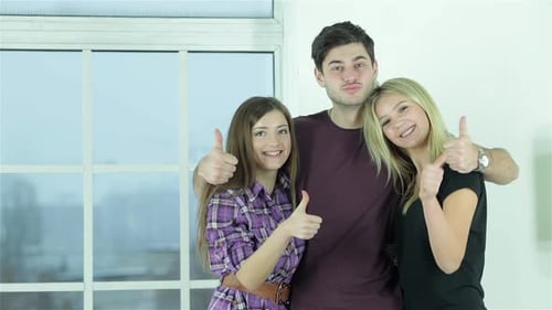 Kerl und zwei Mädchen zeigen Daumen