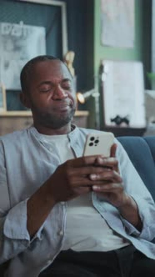 Content Person Browsing and Laughing Comfortably Casual Man Engaged with Social Feed in Cozy Home