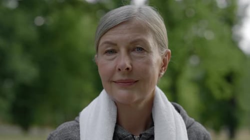 Close Up Portrait of the Smiled Mature Woman in Sporty Clothes Standing in the Park Carrying Towel