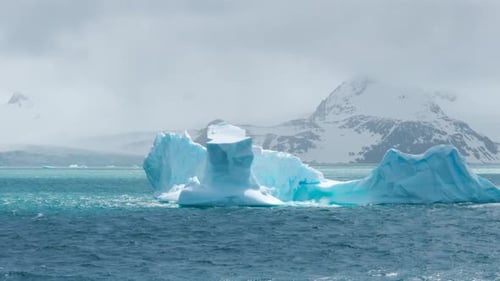 Iceberg azul de la Antártida con montañas cubiertas de nieve en el fondo. Hielo flotante, tierra grande y hermosa