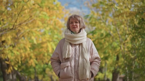 Woman Adjusting Scarf in Autumn Park