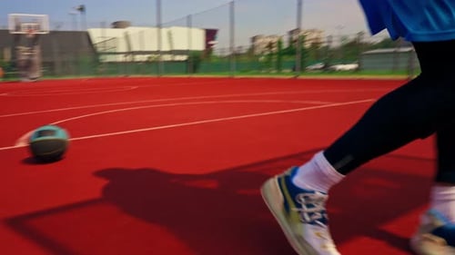 A tall guy basketball player throws a ball into a basketball hoop at a basketball court in the park