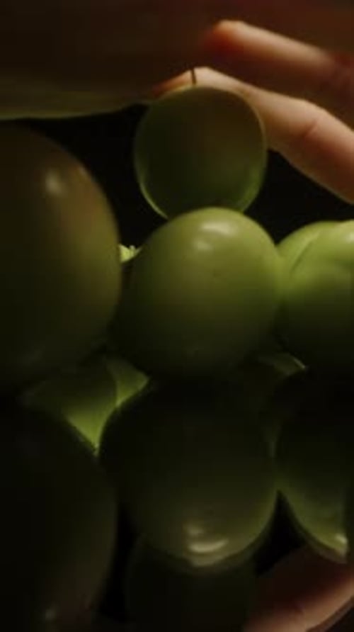 Vertical video. Unripe Green Cherry Plums on a Black Table, Dolly Slider Extreme Close-up. Hand