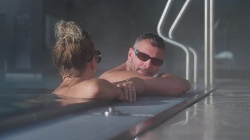Couple Relaxing Together in Indoor Swimming Pool