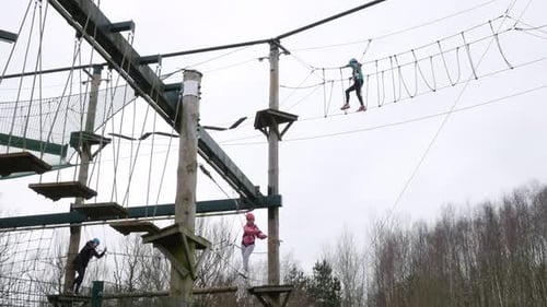 Girl walking across a rope bridge on a high wire adventure obstacle course