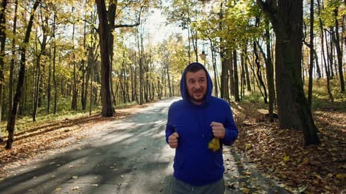A Man Runs on Yellow Leaves in an Autumn Park