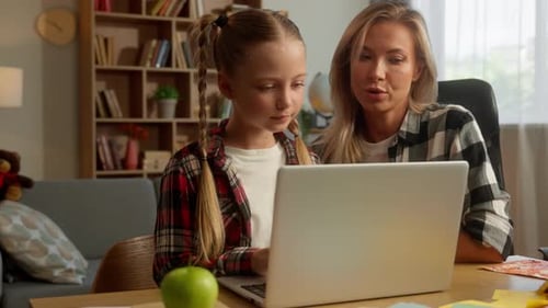Mother Helping Daughter with Homework on Laptop
