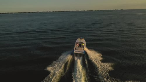Motorboat Cruising Across Water at Golden Sunrise
