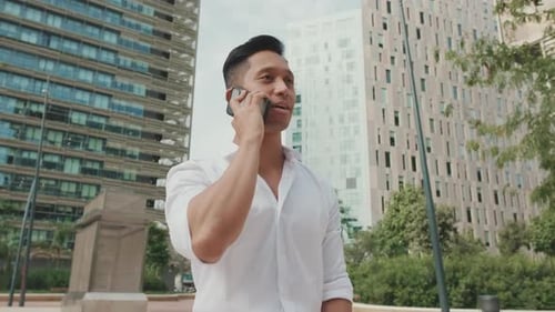 Man Talking on Phone Outdoors Reacts Positively