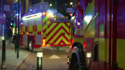 Urban Emergency Vehicles Lining Residential Street at Night with Warning Lights Flashing City