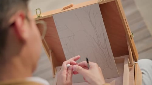 Man Sketches Landscape on Drawing Board Indoors