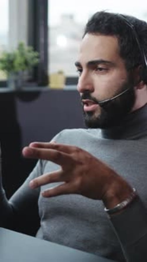 A Focused Young Man Wearing a Professional Headset While Working in a Modern Office Setting