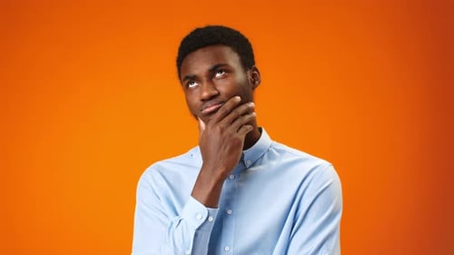 Thoughtful Man Ponders Options on Orange Background