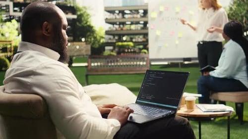 African American Businessman Coding on Laptop Terminal Window on Terrace