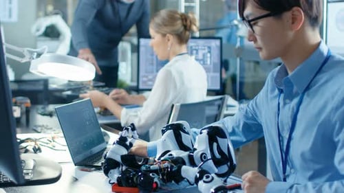 Elektronikingenieur arbeitet mit dem Roboter und manipuliert seine Reaktionen Laptop, leitende Ingenieure