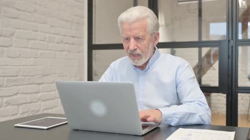 Excited Senior Businessman Celebrating Success on Laptop in Office