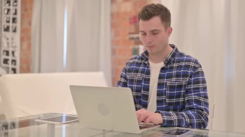 Man Typing on Laptop at Glass Table