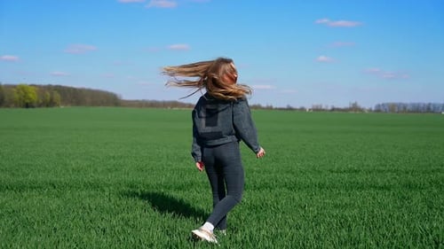 Happy girl in jeans on a green meadow.