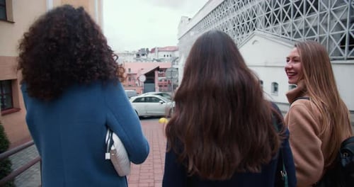 Camera Follows Three Happy Beautiful Young Women Friends Walking Along Autumn City Street Enjoy