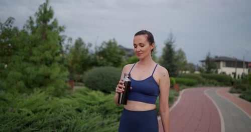 Woman Drinks Water after Outdoor Exercise