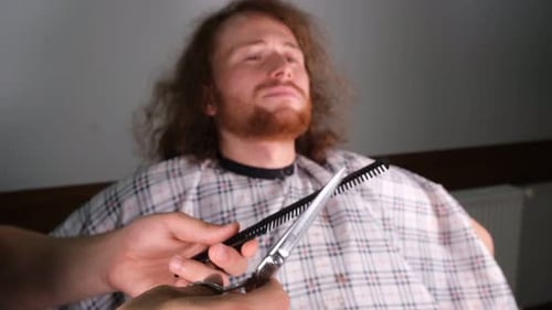 Young Adult Receives Haircut Indoors With Cape